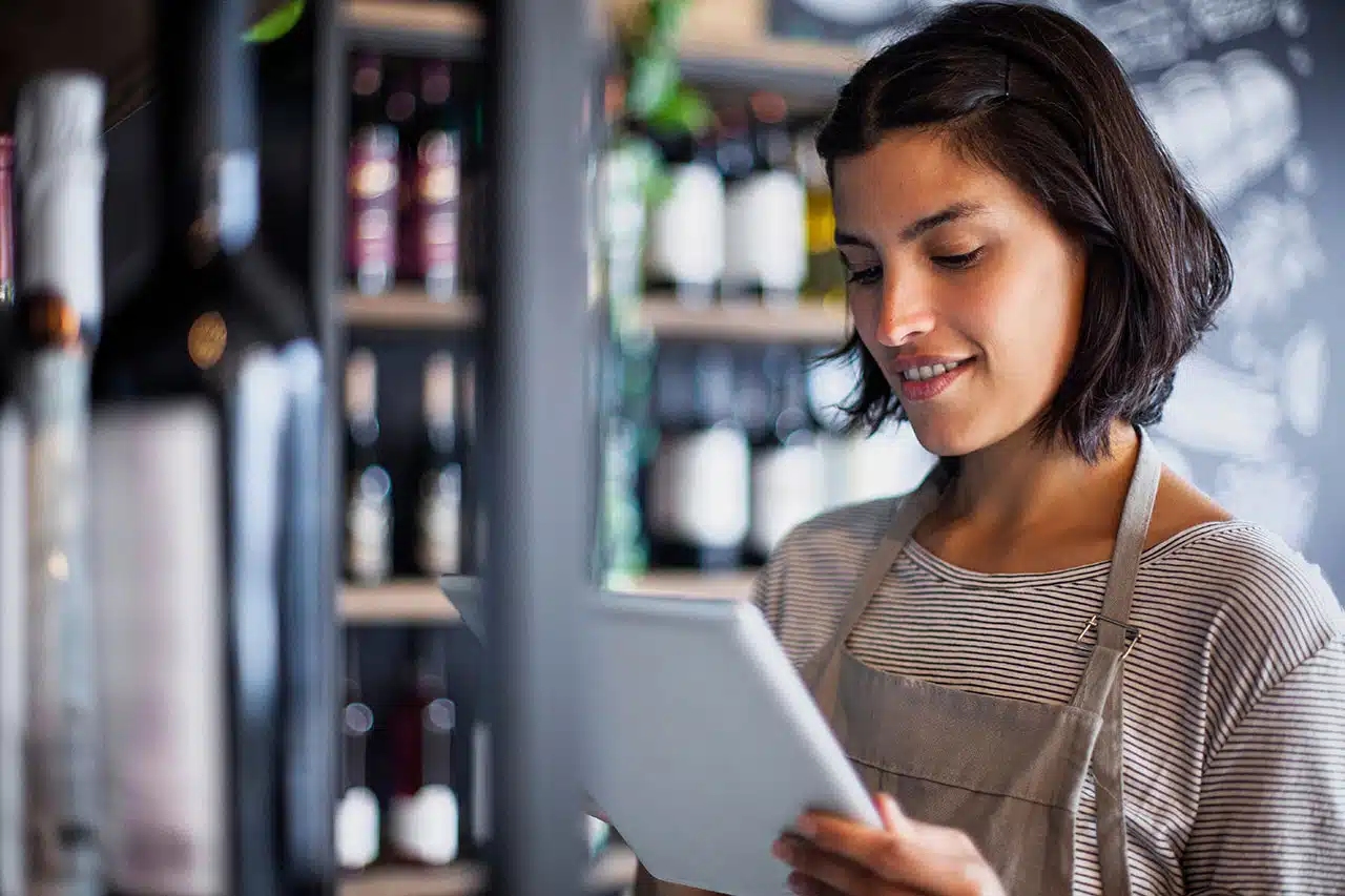 liquor store worker taking inventory of bottles on digital tablet liquor store worker taking inventory of bottles on digital tablet