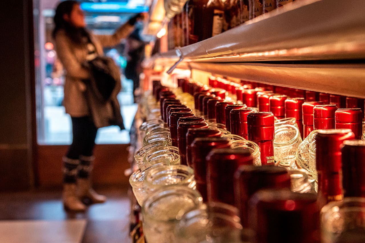 a shelf or liquor with a woman examining bottles down the isle a shelf or liquor with a woman examining bottles down the isle
