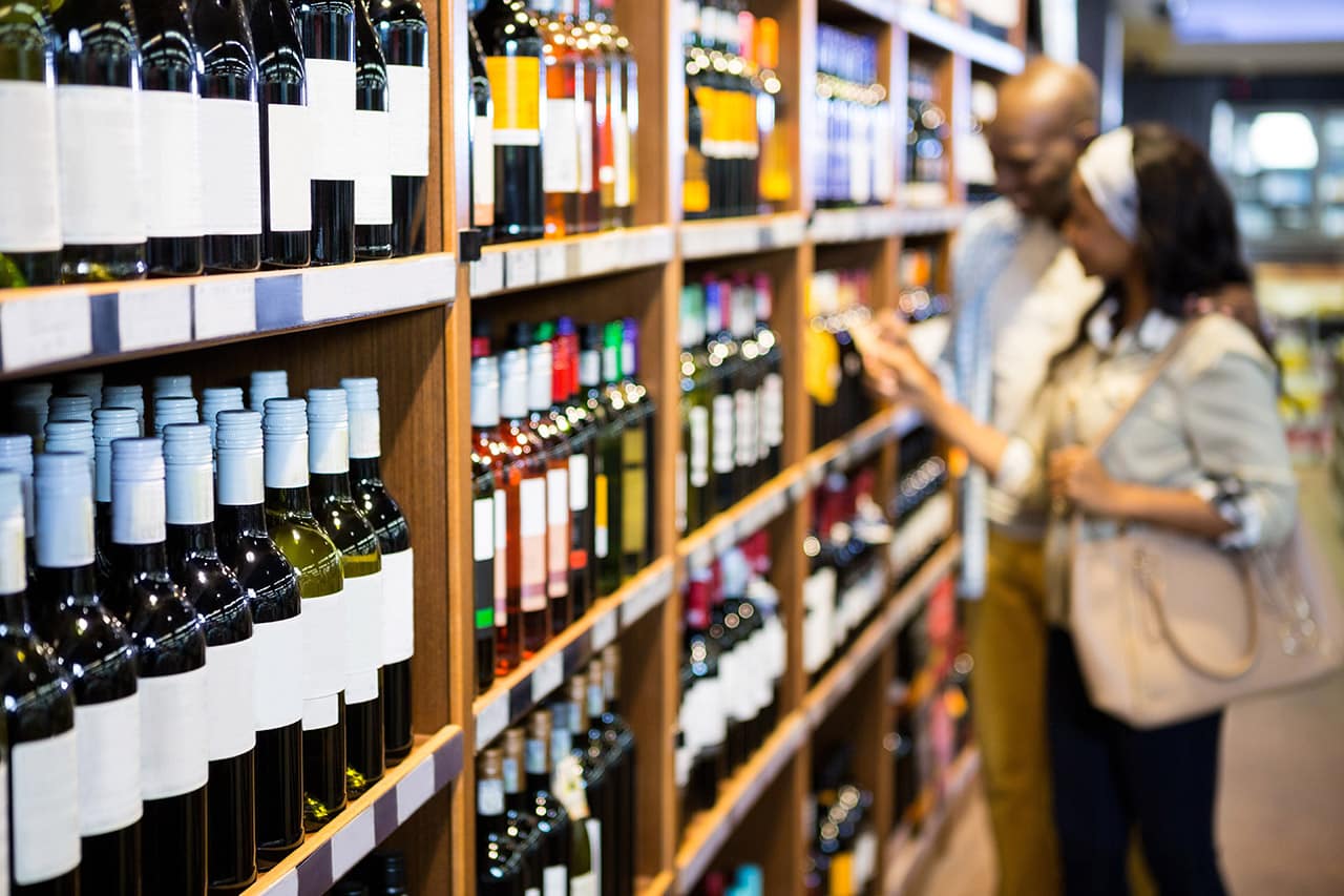 Couple looking at wine bottle in grocery section couple looking at wine bottle in grocery section